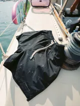 Short de baño negro con estampado de palmeras en color beige, cintura elástica con cordón ajustable y logo de la marca en la pierna izquierda.