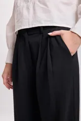Pantalón de vestir negro, de corte carrot, con bolsillos laterales y traseros.