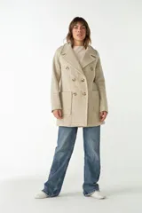 Abrigo de lana color beige con cuello solapa y manga larga. Cierre frontal cruzado doble con botones dorados. Bolsillos delanteros plaqué y forro al tono. Tela 100% lana fina sin teñir, diseñada exclusivamente por Don Baez. Hecho 100% en Uruguay.