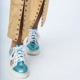 Zapatillas bajas de cuero con paneles en verde, dorado y plateado. Aplique de estrella rosada en el lateral y cordones blancos.