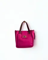 Cartera minibag color fucsia de cuero, con manijas cortas color marrón y cierre metálico frontal.