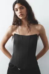 Top bustier negro de satén con escote corazón y hombros descubiertos. Cierre trasero con cremallera metálica.