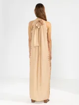 Vestido largo color naranja con estampado de flores rosas, corte recto, cuello halter y espalda descubierta.