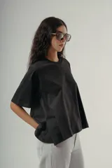 Camiseta negra de algodón con corte amplio y mangas cortas. Presenta un pequeño bordado sutil en el pecho.