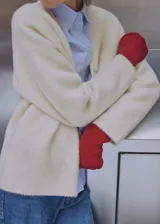 Cardigan color crema de tejido suave con efecto pelo. Tiene escote de pico, cierre frontal con botones y mangas largas.