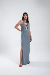 Vestido largo de punto color gris, con cuello redondo, sin mangas y abertura lateral en la falda. Presenta un adorno de piedras ágatas engarzadas en el escote.