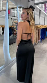 Vestido largo negro con escote halter, abertura en el abdomen y tajo en la pierna.
