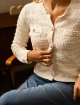 Cardigan de tejido tweed color blanco, marca Catherine Malandrino. Tiene cuello a la base, abertura central con botones perlados, bolsillos simulados en la delantera y bordados en lurex y lentejuelas.