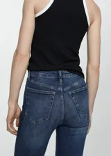 Jeans de tiro alto color azul oscuro, corte skinny, cinco bolsillos, cierre con cremallera y botón, confeccionados en tejido de algodón estilo tejano vaquero.