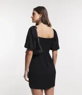 Vestido corto negro de viscosa con escote cuadrado, mangas cortas abullonadas, lastex en la espalda y abertura en el bajo.