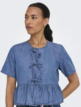 Camisa de denim celeste con lazo. Diseño de cuello camisero, mangas cortas tipo box y calce regular. Incluye detalle de lazo y recorte en la cintura.