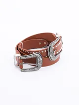 Cinto negro de cuero sintético con hebilla doble de estilo western en metal plateado, con grabados florales y detalles de tachas redondas plateadas.