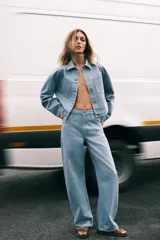 Pantalón de jeans celeste claro, de tiro medio, corte tapered y largo hasta el tobillo. Tiene cinco bolsillos, trabillas en la cintura y cierre frontal con cremallera y botón.