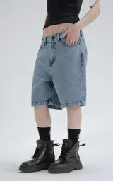 Bermuda de denim azul claro con efecto desgaste, corte oversize y estilo carpintero con bolsillo lateral.