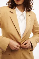 Blazer color beige entallado, con corte en la cintura y cierre con un botón.