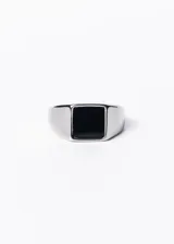 Anillo plateado de acero quirúrgico con piedra negra rectangular en el centro.