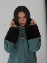 Campera corta negra con cuello y puños de piel sintética negra. Cierre con presillas de madera.