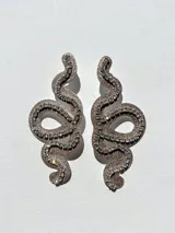 Par de aros colgantes con forma de serpiente contorneada en strass y cierre a presión de acero inoxidable.