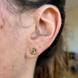 Par de aros pequeños de plata 925 con acabado en oro de 18k, con forma circular y circonitas de colores.