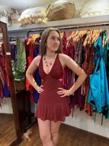 Vestido corto de lentejuelas color verde oliva, con escote en V, breteles finos cruzados en la espalda, cut-outs laterales y volado en el ruedo.