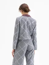 Chaqueta corta (cropped) con estampado a cuadros gris y azul claro, cuello solapa de cuero color bordó y bordados a juego. Presenta bolsillos con tapa en el frente y mangas con puños acampanados.