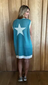 Vestido corto de tejido de algodón color celeste, con cuello redondo y sisas amplias. Presenta un estampado de una estrella blanca grande en la espalda y ribete blanco en el ruedo.