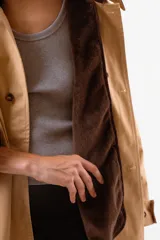 Chaqueta tipo sobrecamisa o abrigo ligero color camel, con cuello solapa de color marrón oscuro, cierre frontal de botones y bolsillos laterales.