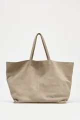 Bolso tipo maxi shopper color beige de ante, con doble asa de hombro y bolsillo interior con cremallera.