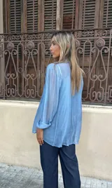 Camisa de seda celeste de manga larga, con botones frontales y corte holgado. Se vende como parte de un conjunto con una musculosa al tono.