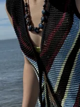 Chaleco calado negro con diseño de rayas diagonales rojas, beige y blancas.