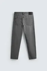 Jeans de denim de algodón, color negro lavado, con tiro medio, corte ajustado en cadera y muslos, y pierna que se estrecha hacia el tobillo. Presenta cinco bolsillos y cierre frontal con cremallera y botón.