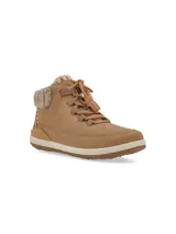 Botín color tostado, confeccionado en cuero y textil en el cuello de la caña, con detalles bordados y acabados de pompones en los cordones. Su suela, equipada con la tecnología Honey Foam de RKF, ofrece liviandad, flexibilidad y excelente amortiguación.