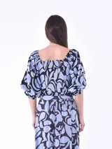 Blusa corta con estampado de hojas en tonos celeste y negro, escote cuadrado, mangas abullonadas 3/4 y cierre frontal con botones blancos.