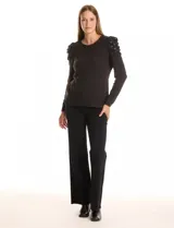 Buzo negro de tejido suave, marca Zac & Rachel, con cuello a la base y manga larga. Presenta hombros plisados y decorados con perlas.