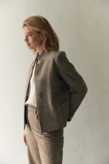 Chaqueta corta color marrón con cuello solapa, manga larga con coderas aplicadas, cierre frontal con botones y bolsillos ojal. Con forro. Tela 100% lana fina sin teñir, diseñada exclusivamente por Don Baez. Hecha 100% en Uruguay.