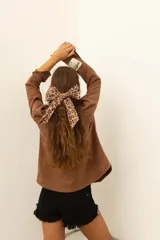 Camisa marrón de corte recto con cuello camisero, cierre frontal con botones, mangas largas con puños abotonados y bolsillos de parche en el pecho.