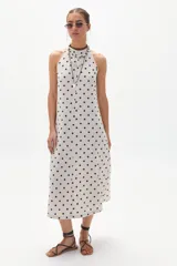 Vestido midi de lino color crudo con lunares negros, escote halter y espalda con cierre invisible y botón al cuello.