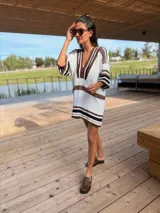 Vestido corto tejido en hilo de algodón color blanco con rayas horizontales marrones y negras, escote en V y mangas cortas.