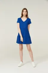 Vestido corto lila con cuello en V y mangas cortas. Tiene corte holgado y dos volados en la falda.