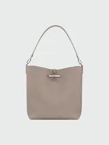 Bolso tipo hobo de cuero color negro, con asa de hombro ajustable y cierre superior con broche metálico.