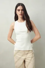 Musculosa blanca de punto canalé fino, sin mangas y con lazos ajustables en los laterales.