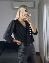 Blusa negra con estampado de lunares blancos, escote en V cruzado, mangas 3/4 abullonadas y hombreras. Talle único abarca hasta L.