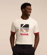 Remera de algodón color crema con cuello redondo y mangas cortas con ribete rojo. Estampa frontal con el logo de Kodak.