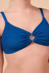 Top de bikini azul con textura, sin aro y con detalle de aro en el centro. Breteles regulables y nudo regulable en la espalda.