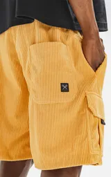 Bermuda cargo color mostaza de corderoy liviano, con bolsillos amplios con solapa, fuelle y detalles en cinta gross, elástico en la cintura y calce oversize.