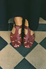 Sandalias tipo cangrejeras planas de cuero negro, con tiras cruzadas en la parte delantera, puntera redondeada y cierre mediante tira con hebilla al tobillo.