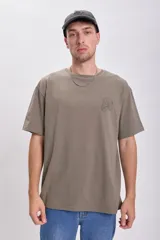 Remera gris de corte amplio con cuello redondo y mangas cortas. Presenta un pequeño estampado en el frente con un diseño geométrico.