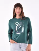 Remera verde con diseño gráfico frontal, de manga larga y corte relajado.
