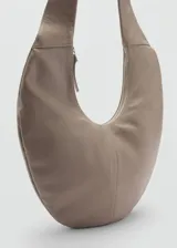 Bolso bandolera grande de cuero color gris topo, con forma de media luna y asa ajustable. Cierre superior con cremallera y forro interior de algodón.
