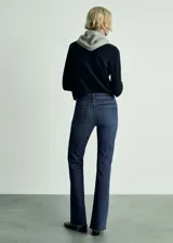 Pantalón de jean azul oscuro, de tiro medio, corte flare y terminación desflecada.